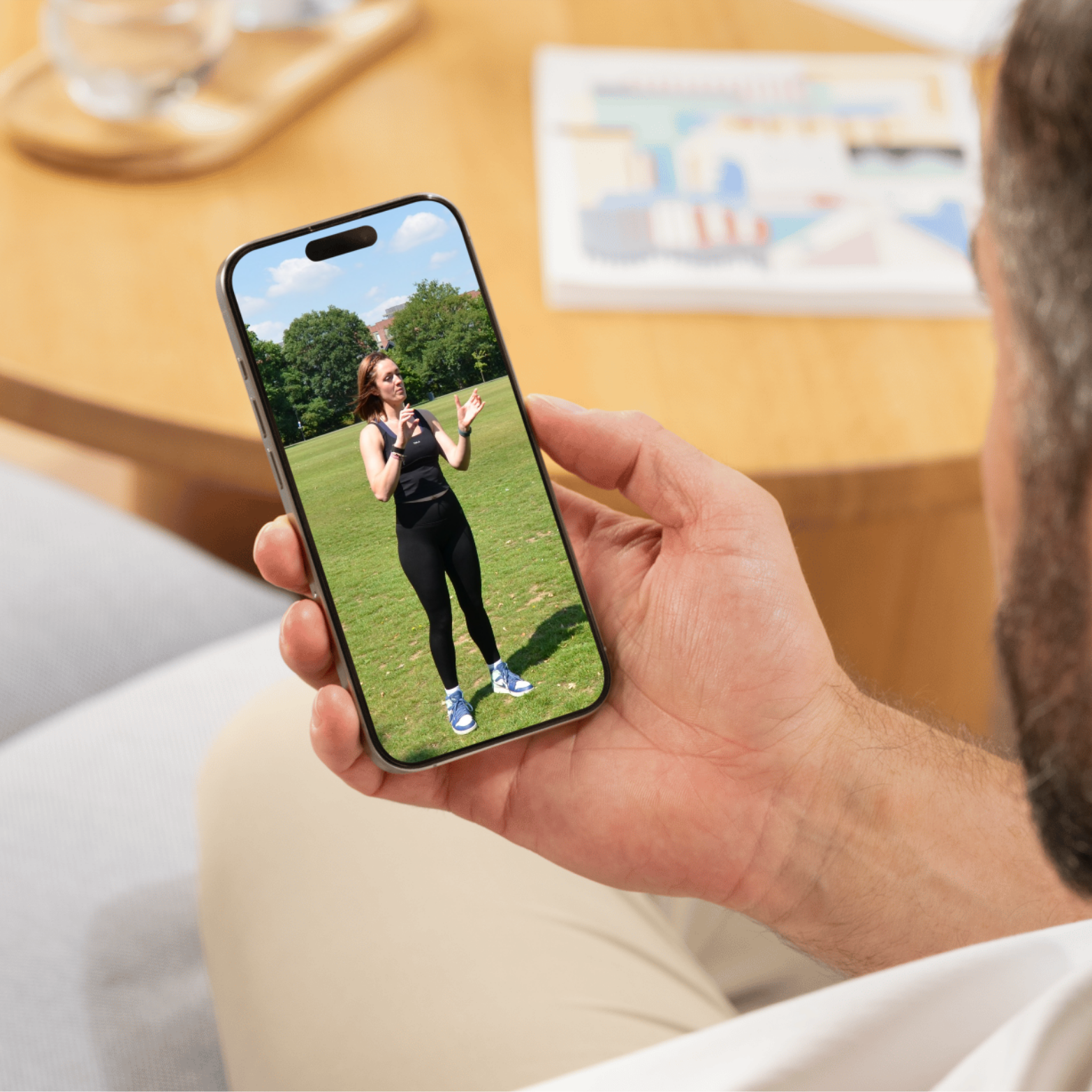 Close-up of a smartphone showing a video of Charlotte from Solace Strength speaking outdoors in activewear on a green field.